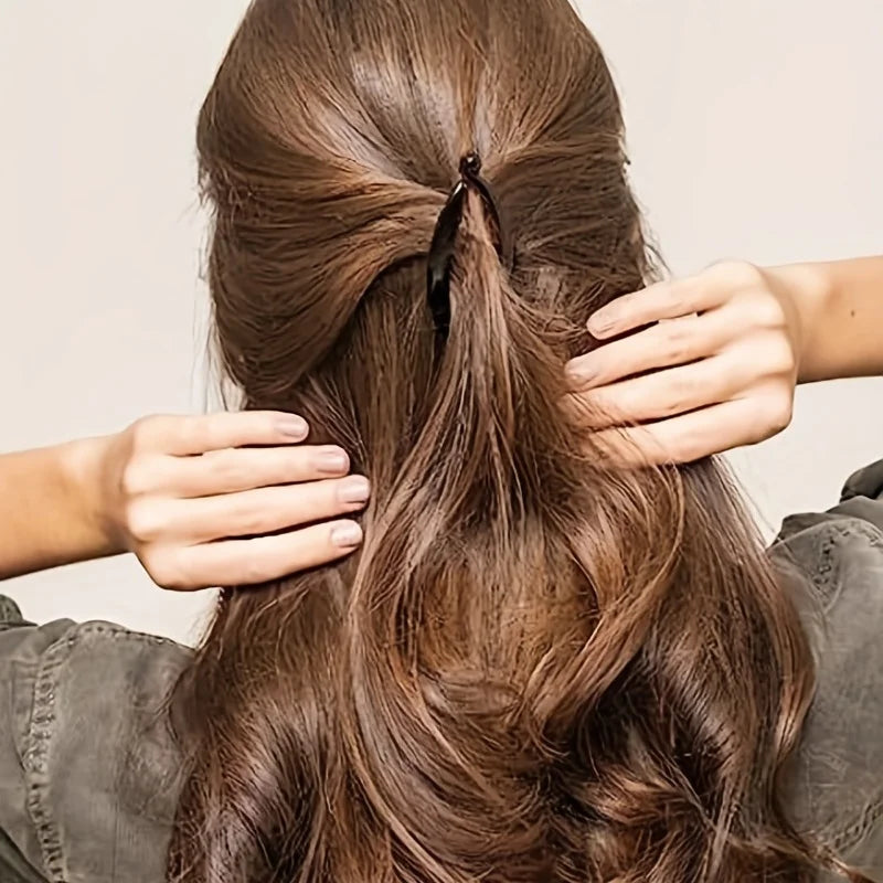 Woman styling her hair with a matte banana hair clip, showcasing an elegant ponytail.