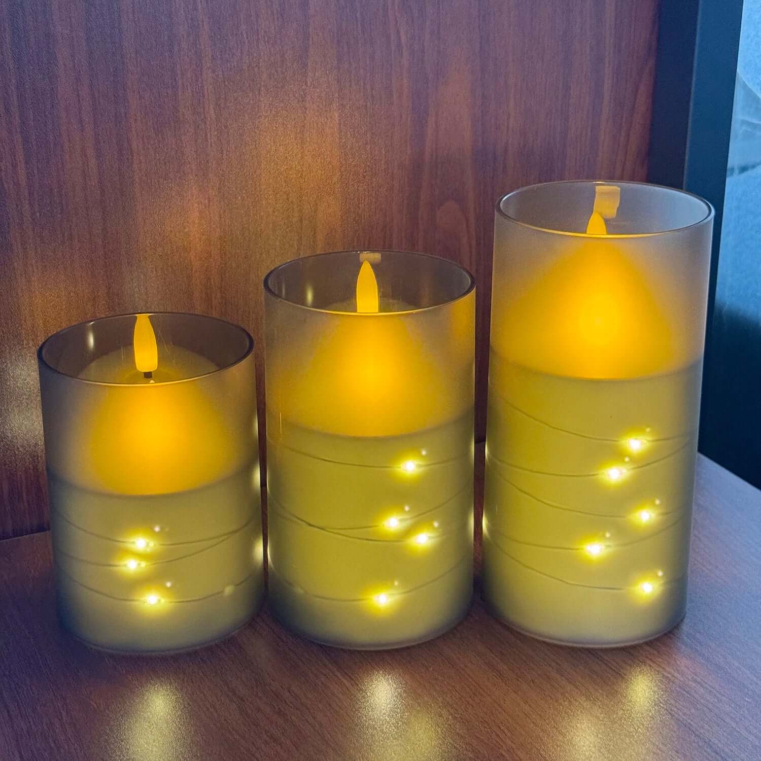 Set of three LED electronic candles glowing with warm yellow light, perfect for decor during Christmas and weddings.