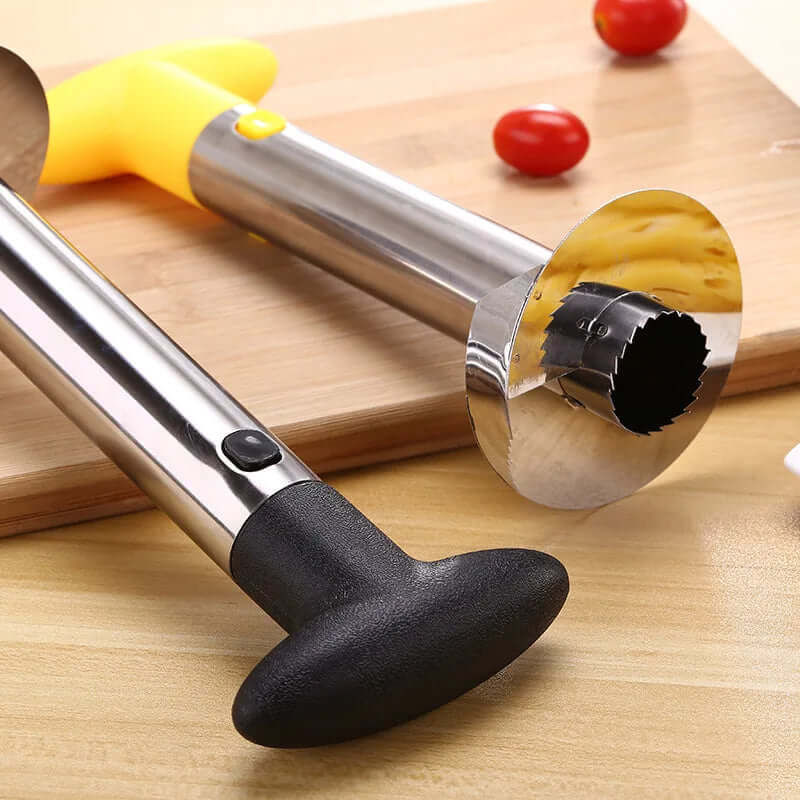 Stainless steel pineapple peeler and corer tool with ergonomic handle on a wooden cutting board.