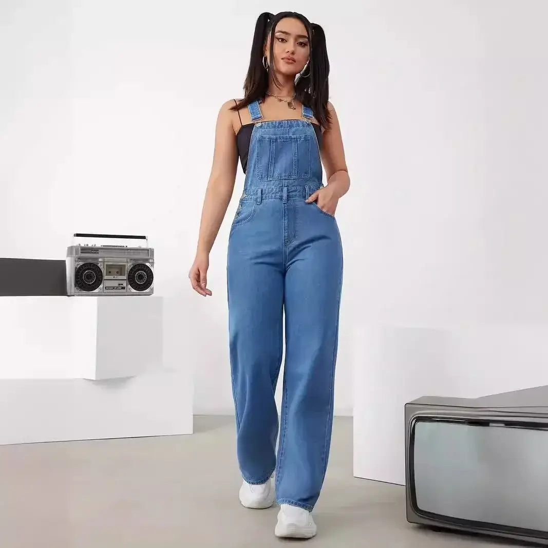 Stylish woman in a sleeveless women's denim bib jumpsuit, walking confidently with retro accessories.